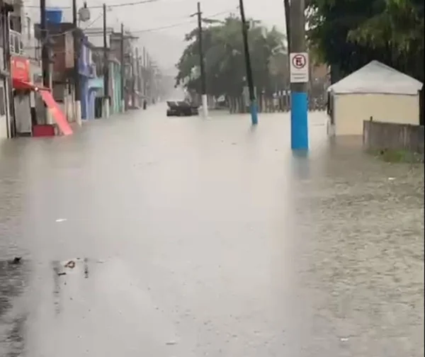 Imagem colorida mostra rua alada durante chuva. Água bate a altura de quase 30 centímetros em poste de trânsito