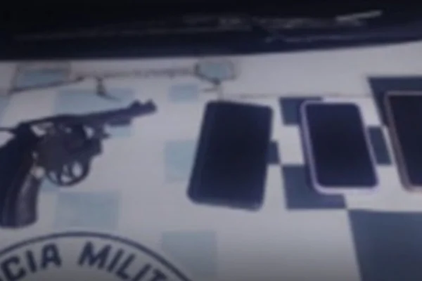 Imagem colorida de celulares e um revólver apreendido em posse dos adolescentes abordados pela PM - Metrópoles