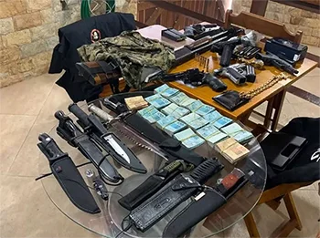 Conteúdo apreendido na casa do policial penal Alcimar Badaró Jacques, o Badá em operação do MPRJ. Sob mesas, vários maços de dinheiro, facões, facas, armas, coletes à prova de balas, projéteis e outros materiais - Metrópoles