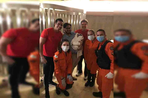 Equipe dos bombeiros posa para foto com bebê no colo