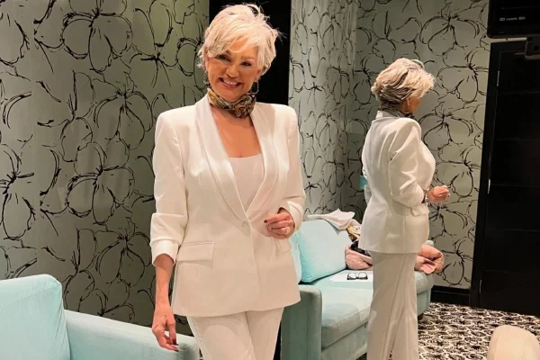 Mulher branca e loira de cabelos curtos vestindo terno branco