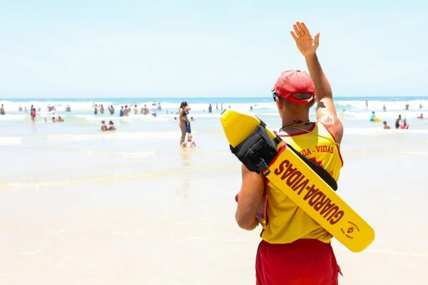 Imagem colorida de bombeiro em praia evitando afogamentos - Metrópoles