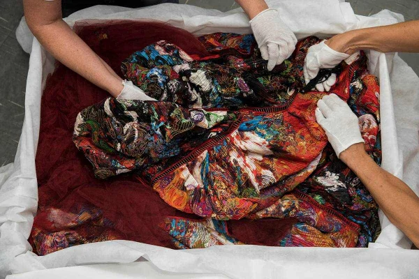 Mão com luvas mexem em tecidos coloridos - Metrópoles