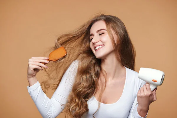 Foto colorida de uma mulher penteando o cabelo - Metrópoles
