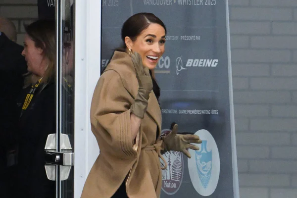 Foto colorida de Meghan Markle usando um casaco marrom saindo de uma loja - Metrópoles