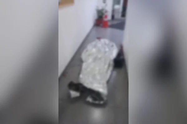 Imagem colorida mostra corpo coberto por manta. Ele é um homem que invadiu base da PM e levou tiros dos agentes - Metrópoles