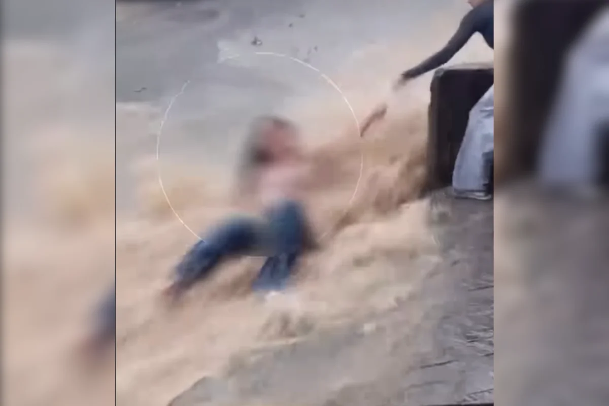 Jovem é resgatada após ser arrastada por enxurrada na rua e parar em poste