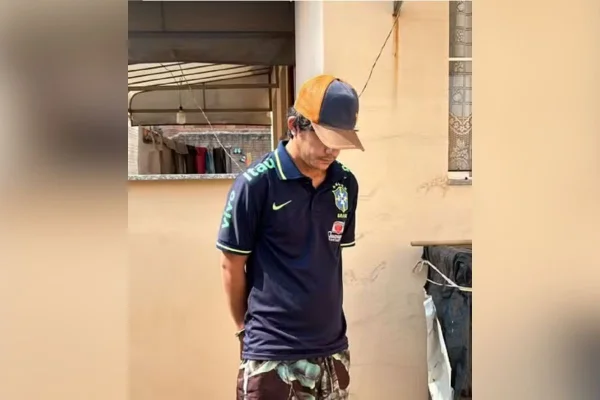 Imagem colorida mostra homem algemado com boné e camisa da seleção brasileira. Ele era procurado pelos atos golpistas de 8 de Janeiro e candidato a vereador no interior de SP - Metrópoles