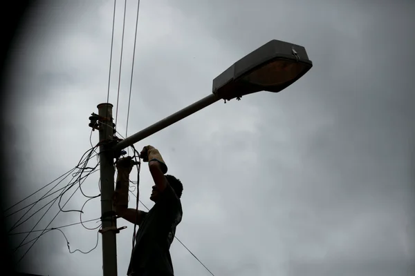 Ligação clandestina na rede de energia eletrica. Homem faz gato na rede de energia elétrica