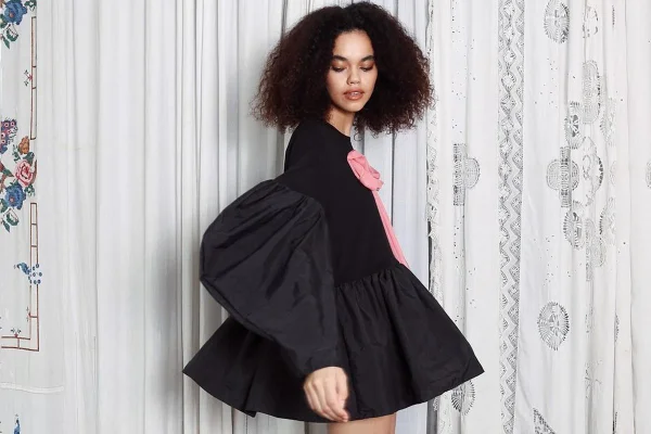 Na imagem com cor, mulher posa em fundo listrado com look preto - Metrópoles