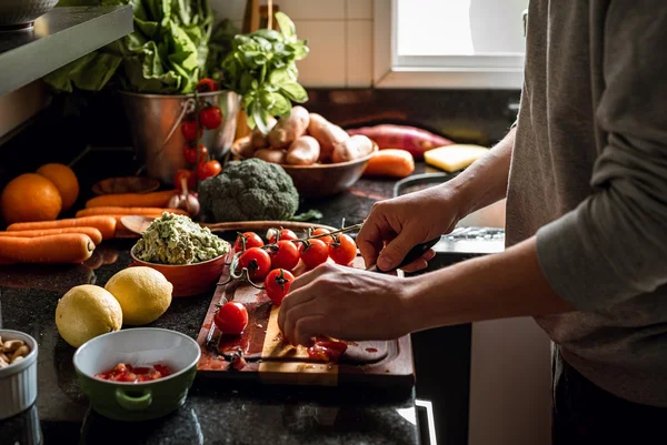 Imagem mostra mulher cortando tomates e mesa cheia de vegetais - Metrópoles