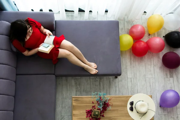 Imagem colorida de pessoa descansando no sofá no meio da festa - Metrópoles