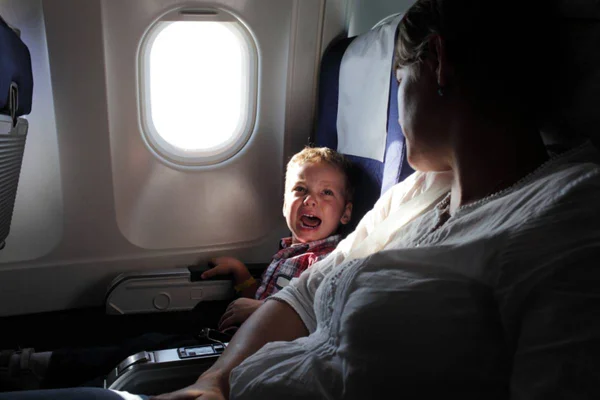 Imagem colorida de criança que chora em viagem de avião ao lado de mãe - Metrópoles