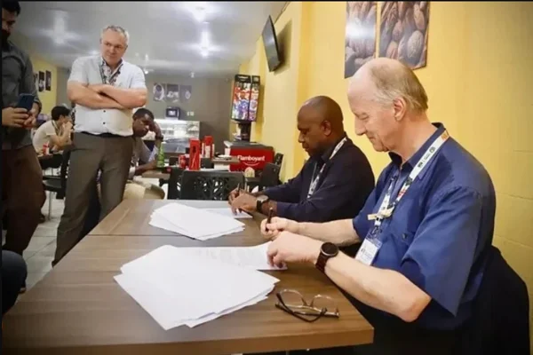 Imagem colorida de homem assinando papel em mesa - Metrópoles