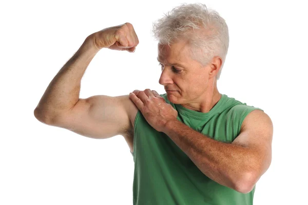 Retrato de homem idoso flexionando bíceps isolado sobre fundo branco. Bíceps, câncer, musculatura
