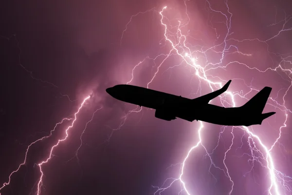 Imagem de avião, em voo, se aproximando de nuvens carregadas e com raios e trovões ao fundo; rotas com turbulência - Metrópoles