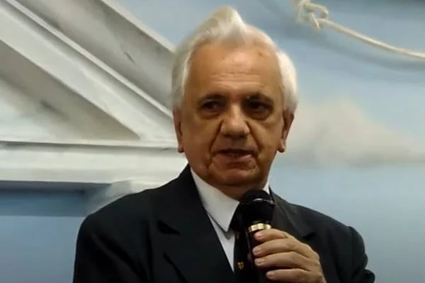 Imagem colorida de homem grisalho segurando microfone