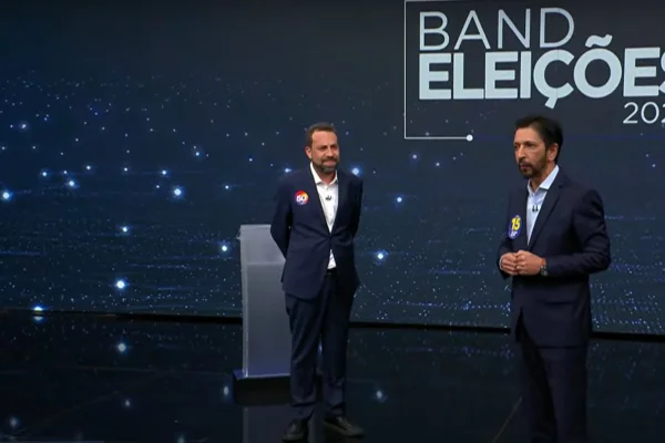 Imagens coloridas mostram à esquerda, homem branco, barbado, termo azul e camisa branca, sorrindo, de lado e olhando para homem, à direita, branco, terno e camisa azuis, falando com o olhar para frente