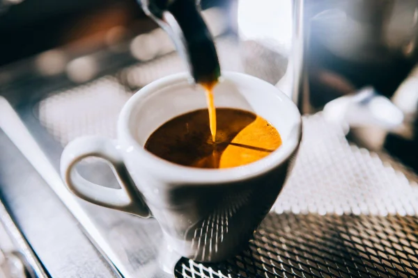 Imagem mostra café expresso sendo colocado em uma xícara branca - Metrópoles