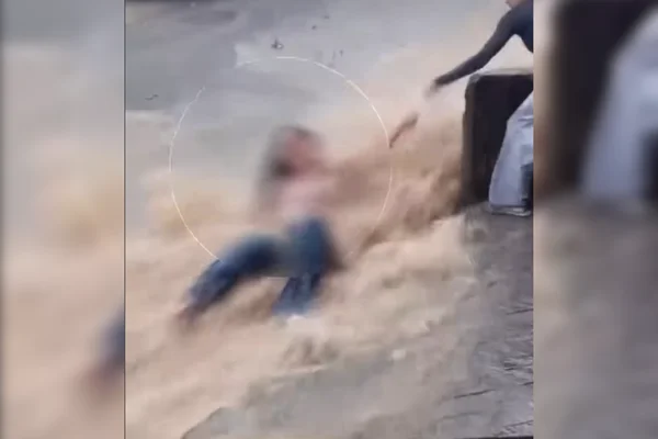 Imagem colorida de jovem sendo arrastada por enxurrada na rua - Metrópoles