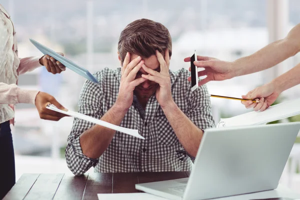 Homem estressado e frustrado com dispositivos eletrônicos no escritório. Metrópoles