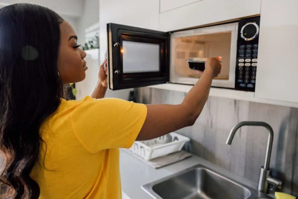 Imagem colorida de mulher usando micro-ondas