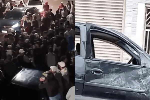 Imagem colorida de um carro preto completamente destruído com partes amassadas e vidros quebrados - Metrópoles