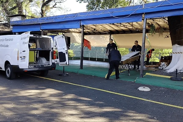 Imagem colorida de um homem em situação de rua caído no chão e velado com plástico - Metrópoles