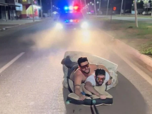 Imagem colorida de influencer César Rincón "surfando" em um colchão nas ruas de Confresa - Metrópoles