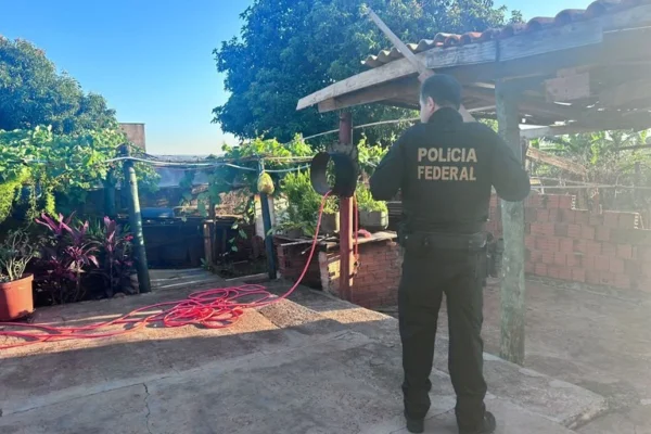 Imagem colorida mostra homem de pé, virado de costas, vestindo roupas pretas com Polícia Federal escrito nas costas - Metrópoles