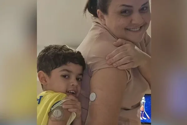 Imagem mostra uma mulher e uma criança mostrando medidor de glicose no braço - Metrópoles