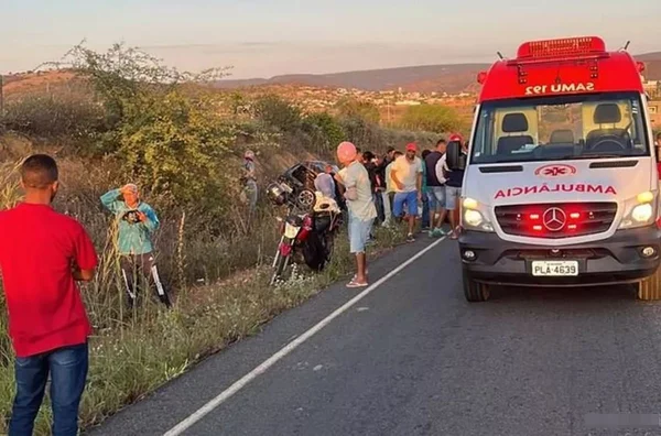 pessoas de reunem na beira de uma estrada após acidente de trânsito. uma ambulância do SAMU está estacionada na pista
