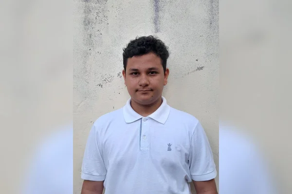 imagem colorida mostra adolescente com blusa modelo polo na cor branca. ele tem cabelo ondulado, pele morena e sorri - metrópoles