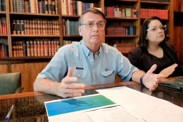 O presidente Bolsonaro, há dois dias de deixar o cargo, faz live no palácio do Alvorada antes de terminar mandato. Ele fala na biblioteca diante da mesa, ao lado de uma tradutora - Metrópoles
