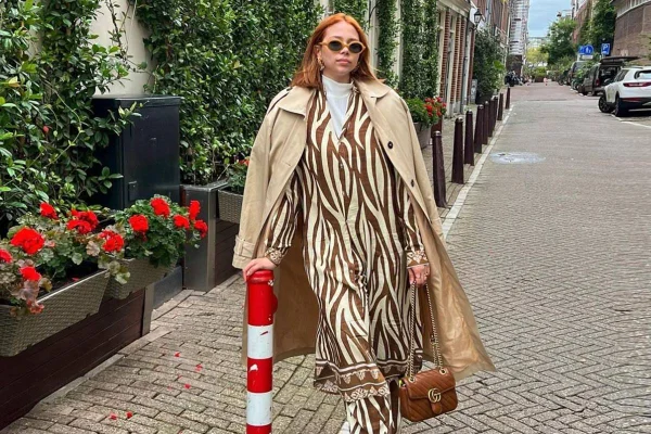Na imagem com cor, mulher branca com o cabelo ruivo posa com look nos tons marrons - Metrópoles