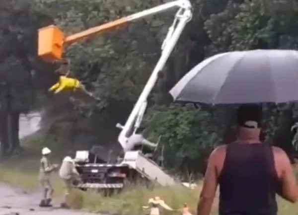 Imagem colorida de funcionário da empresa de energia Enel pendurado após caminhão cair em barranco, no Rio de Janeiro - Metrópoles