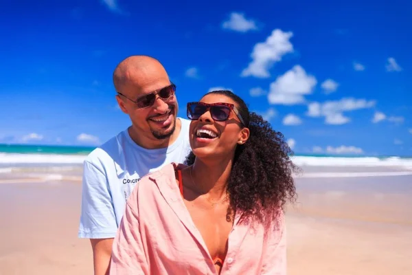 Fernanda Garay e o marido, Márcio Santos, posam abraçados e sorridentes na praia - Metrópoles