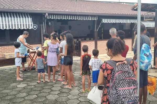 foto colorida de fila de crianças e zeca pagodinho entregando ovos de pascoa - metrópoles