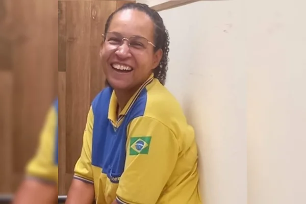 Foto colorida mostra mulher agachada, vestida com uniforme dos Correios. Ela sorri e olha para a câmera
