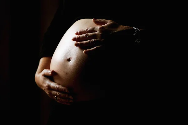 Imagem escura de barriga de mulher grávida. - Metrópoles