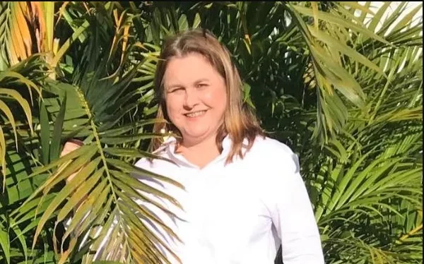 imagem da juiza Kismara Brustoli de camisa branca ao redor de plantas