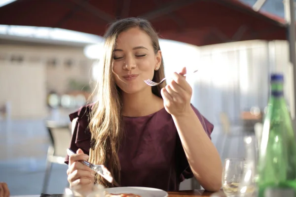 mulher comendo e segurando talheres