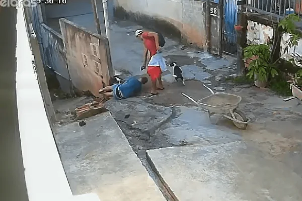 Imagem colorida de uma câmera de segurança, que mostra um homem armado atirando em um outro homem já baleado no chão - Metrópoles