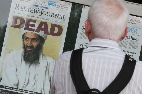 Imagem colorida mostra homem olhando a capa de um jornal em que a morte de Osama Bin Laden é anunciada - Metrópoles