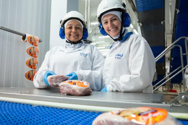 Imagem colorida de duas mulheres trabalhando em um frigorífico da Seara colm uniformes da JBS