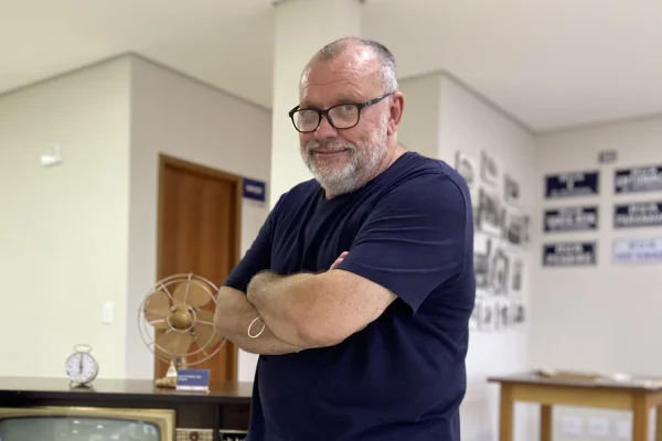 foto de homem de oculos e cabelos brancos e camisa azul escura de braços cruzados
