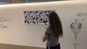 Aluna do La Salle Águas Claras fotografando uma obra da exposição 