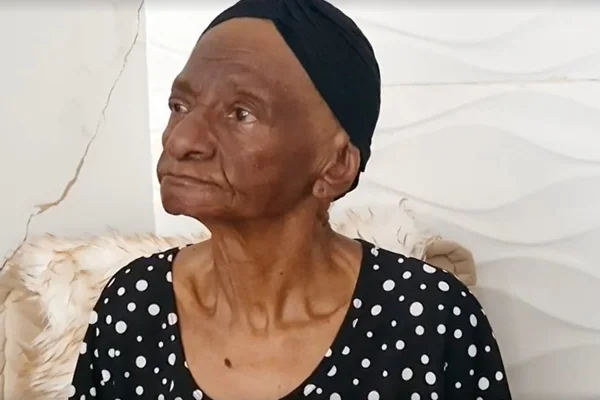 Imagem colorida de Maria de Moura, uma mulher negra e de touca preta na cabeça - Metrópoles