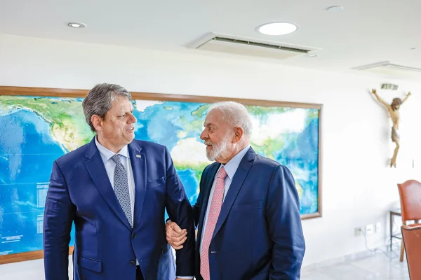 Imagem colorida mostra Lula e Tarcísio, ambos de terno azuis, de braços dados, conversando - Metrópoles