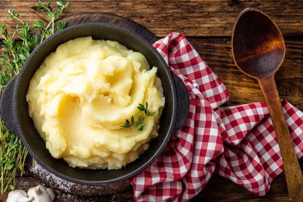 purê de batata dentro de um recipiente marrom com toalha xadrez ao lado